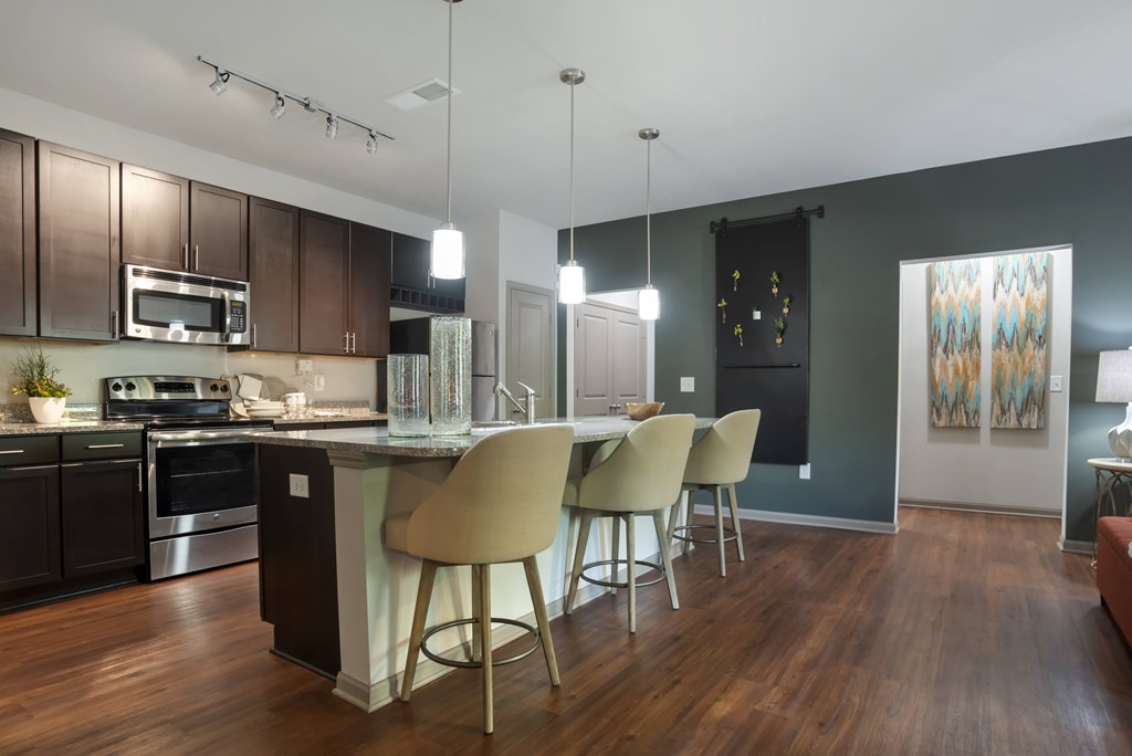 A kitchen with a bar and chairs.